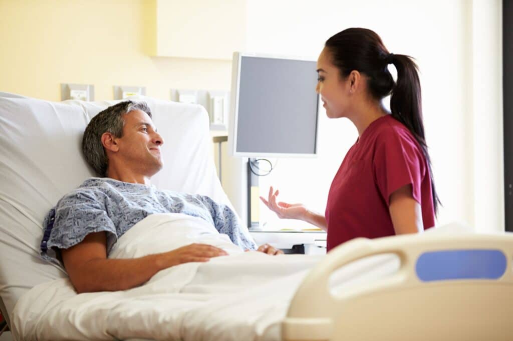 nurse talking to a man in a hospital bed